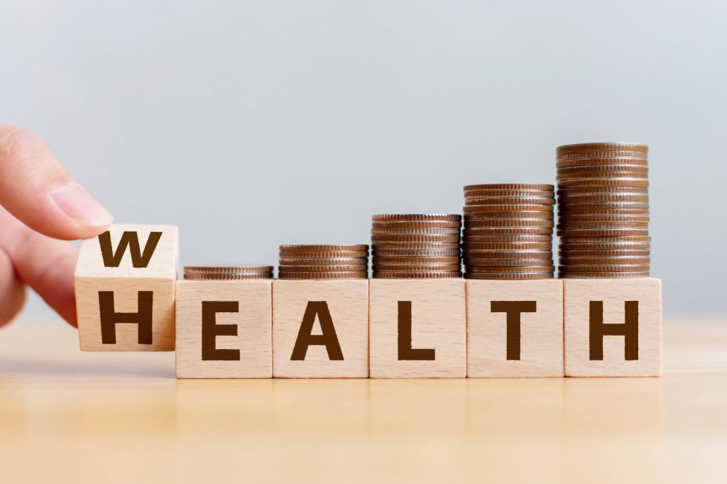 piles of coins on top of wood blocks that spell out wealth or health depending on how the first block is looked at.