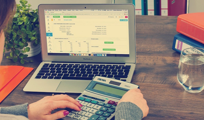 person using calculator in front of a computer