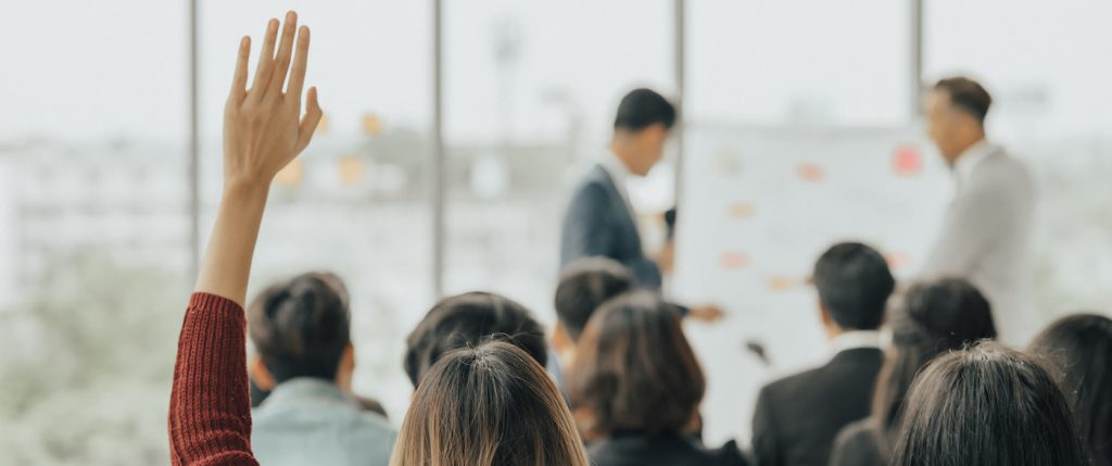 A participant in an employee training program raises their hand to ask a question.